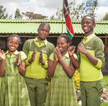Kenyan school pupils stand outside Bridge school with Kenyan flag