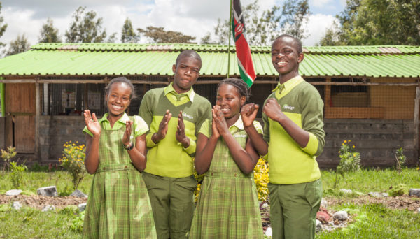 Kenyan school pupils stand outside Bridge school with Kenyan flag