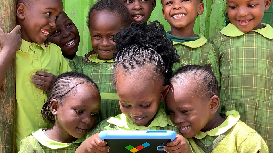 Children gather round a onebillion computer tablet